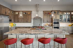 Kitchen featuring built in appliances, recessed lighting, decorative backsplash, dark wood-style flooring, and light stone counters