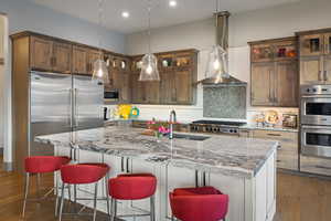 Kitchen featuring built in appliances, backsplash, light stone countertops, and recessed lighting