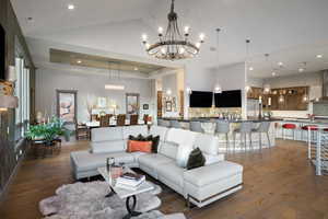 Living area featuring a chandelier, dark wood-style floors, recessed lighting, and lofted ceiling