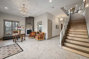 Living area with marble finish flooring, stairway, a chandelier, recessed lighting, and a fireplace
