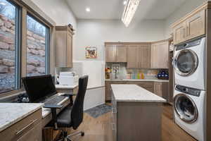 Laundry room with estacked washer and dryer, dark wood finished floors, a desk, recessed lighting, and a chandelier