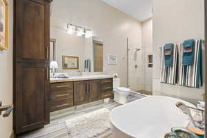 Bathroom with a soaking tub, vanity, a tile shower, and wood finished floors