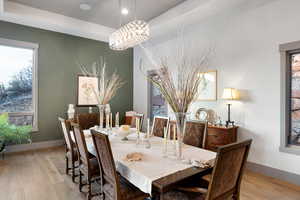 Dining area with light wood-style floors, plenty of natural light, and a chandelier