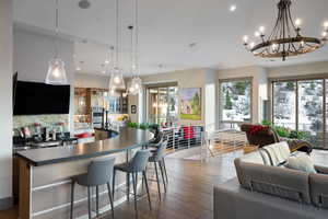 Kitchen featuring dark countertops, a chandelier, open floor plan, dark wood-style floors, and recessed lighting