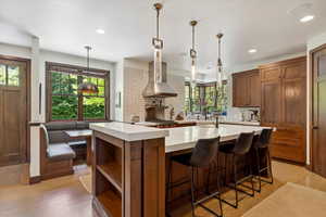 Kitchen featuring wall chimney range hood, light countertops, healthy amount of natural light, decorative backsplash, and recessed lighting