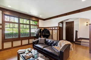 Living area featuring arched walkways, crown molding, wood finished floors, and recessed lighting