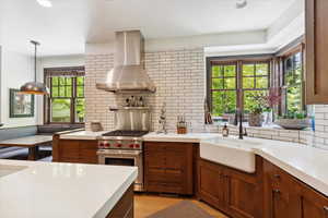 Kitchen with exhaust hood, designer range, backsplash, and light countertops