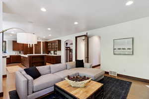 Living room with arched walkways, recessed lighting, and light wood-style flooring
