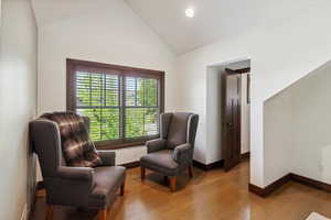 Sitting room with light wood-style floors, high vaulted ceiling, and recessed lighting