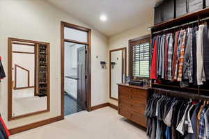 Walk in closet with light colored carpet and lofted ceiling