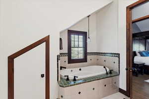 Ensuite bathroom featuring a garden tub and baseboards