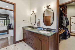 Ensuite bathroom with double vanity, a spacious closet, and recessed lighting