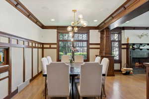 Dining area featuring a chandelier, crown molding, wood finished floors, a tile fireplace, and a decorative wall