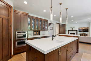 Kitchen with a center island with sink, light wood-type flooring, light countertops, decorative backsplash, and recessed lighting