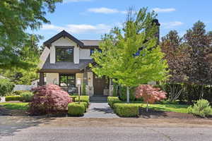 Craftsman-style house featuring a shingled roof, stone siding, and a porch