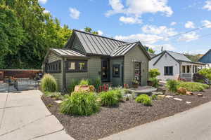 Bungalow-style house featuring a standing seam roof, a gate, and a metal roof