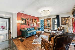 Living area with wallpapered walls, an accent wall, a chandelier, wood finished floors, and a textured ceiling