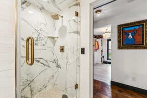 Full bathroom featuring a marble finish shower, wood finished floors, and a chandelier
