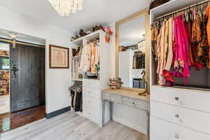 Spacious closet with light wood-style flooring, a chandelier, and a barn door