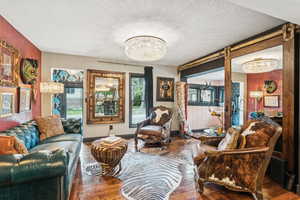 Living room with a chandelier, wood-type flooring, and a textured ceiling