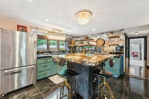 Kitchen with freestanding refrigerator, green cabinets, open shelves, a chandelier, and a kitchen bar