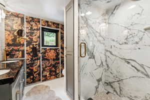 Full bath with vanity and a marble finish shower