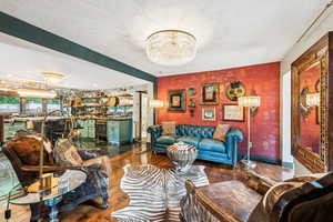 Living area with a chandelier, wood finished floors, and wallpapered walls