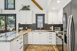 Kitchen featuring stainless steel appliances, recessed lighting, white cabinets, tasteful backsplash, and a peninsula