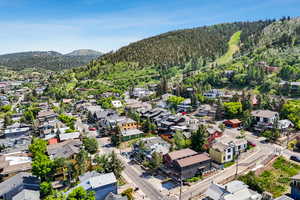 Aerial view of residential area featuring a forest and a mountainous background