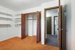 Unfurnished bedroom with light carpet and a closet