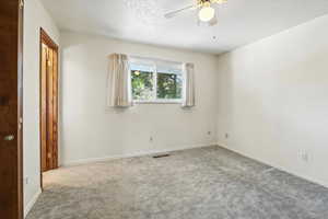 Carpeted empty room featuring a ceiling fan and a textured ceiling