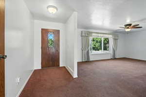 Carpeted entryway with a ceiling fan and a textured ceiling