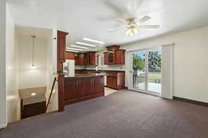 Kitchen with white fridge with ice dispenser, dark countertops, glass insert cabinets, a peninsula, and light colored carpet