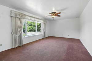 Carpeted empty room featuring ceiling fan and baseboards