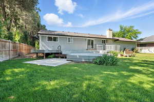 Rear view of house featuring a patio area, a deck, and a chimney