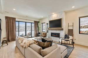 Living room with a tiled fireplace, recessed lighting, and light wood finished floors