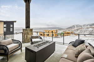 Snow covered patio with a mountain view, a balcony, and an outdoor living space with a fire pit