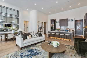 Living room featuring a high ceiling, light wood-style floors, and recessed lighting