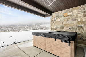 Wooden deck featuring a hot tub, a mountain view, and a patio area