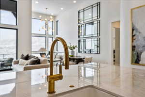 Kitchen view of recessed lighting, a chandelier, and light stone countertops