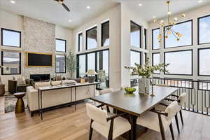 Dining area featuring light wood-style floors, recessed lighting, a ceiling fan, a high ceiling, and a stone fireplace