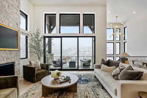 Living room with a mountain view, a fireplace, wood finished floors, plenty of natural light, and a towering ceiling