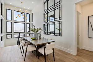 Dining area featuring wood finished floors, a chandelier, a high ceiling, and recessed lighting