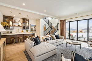 Living room with a mountain view, light wood finished floors, recessed lighting, wet bar, and stairway
