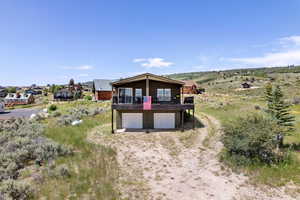 View of front facade with dirt driveway, an attached garage