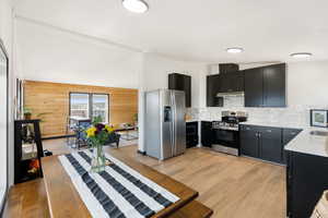 Kitchen featuring brand new stainless steel appliances, under cabinet range hood, quartz countertops, black cabinets