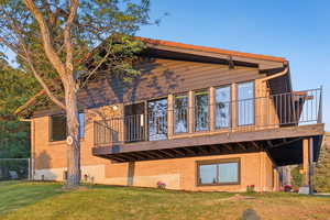Rear view of house featuring brick siding, a yard, and a wooden deck