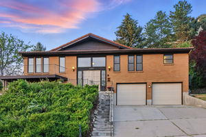 View of front of property with an attached garage, concrete driveway, brick siding, and stairway