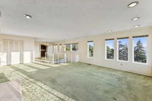 Carpeted spare room with a textured ceiling, a chandelier, and recessed lighting