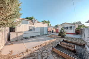 Rear view of house featuring an outbuilding, a vegetable garden, a fenced backyard, and a patio